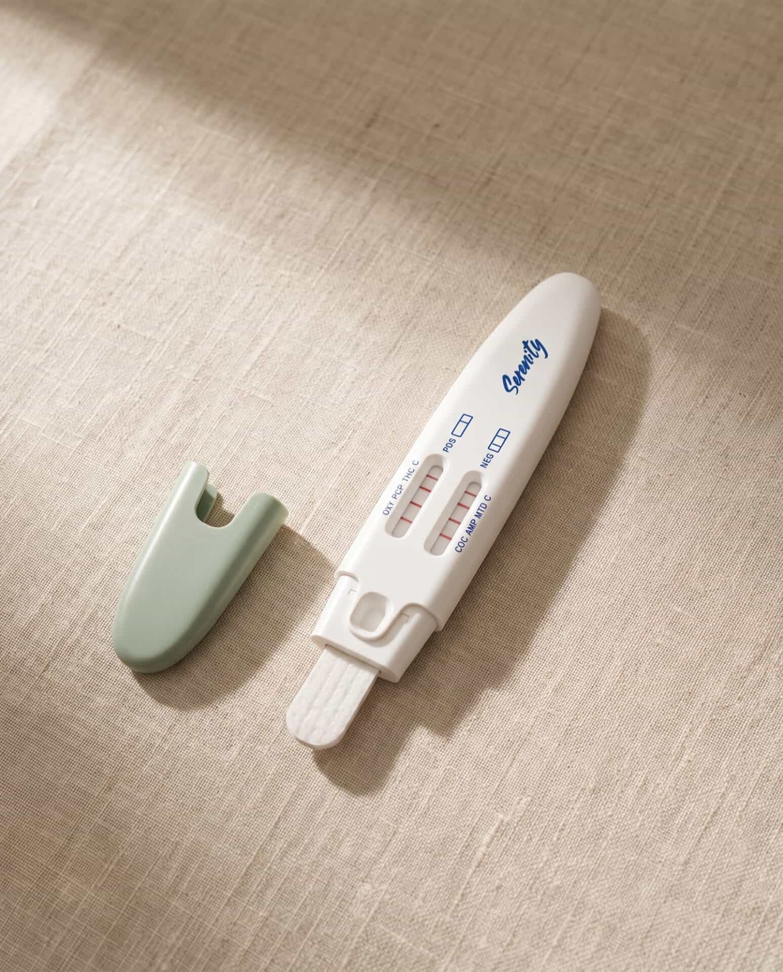 The Serenity 12-panel drug test for oral fluid, uncapped on a warm linen surface, photographed from above in soft natural light.